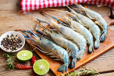 fresh shrimps prawns seafood shelfish with herb and spices chilli pepper lemon lime rosemary, raw shrimp on plate background for cooking food - top viewの写真素材