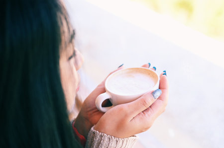 young woman drinking coffee or tea relaxed woman smelling coffee at home in winter with cup coffee, woman coffee with hand holding a cup in cafeの写真素材