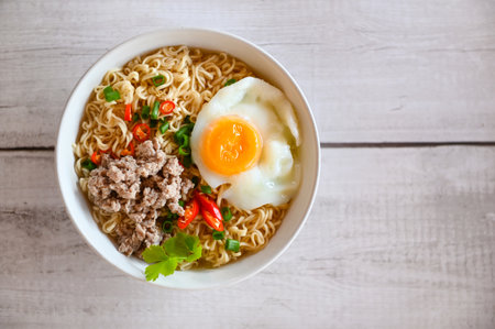 noodles bowl with boiled egg minced pork vegetable spring onion lemon lime lettuce celery and chili on table food , instant noodles cooking tasty eating with bowl noodle soup - top viewの写真素材
