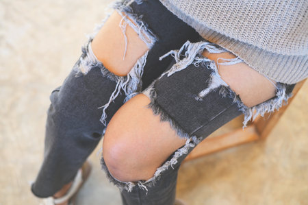 torn pants , torn jeans, close up girl wear jean - women knees in jeans holes in jeans, fashion clothing. Hips and knees in fashionable jeansの写真素材