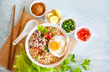 noodles bowl with boiled egg minced pork vegetable spring onion lemon lime lettuce celery and chili on table food , instant noodles cooking tasty eating with bowl noodle soup - top viewの写真素材