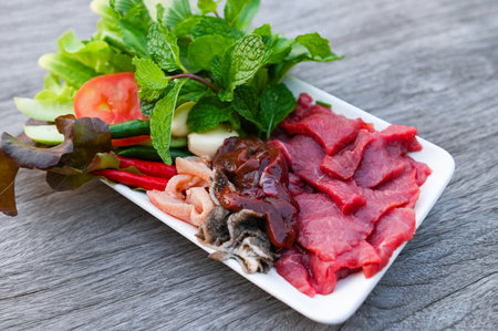 raw beef meat cuts slices on white plate and fresh vegetables fresh meat top view - beef sashimi , beef liver asian thai foodの写真素材