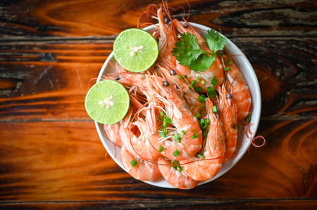 shrimp on white bolw and wooden background dining table food, Fresh shrimps prawns seafood lemon lime with herbs and spice, top viewの写真素材