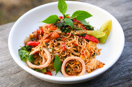 noodles plate with instant noodles stir fried with vegetables herb spicy tasty appetizing asian noodles mix seafood stir fried squid with basil and chilli pepperの写真素材