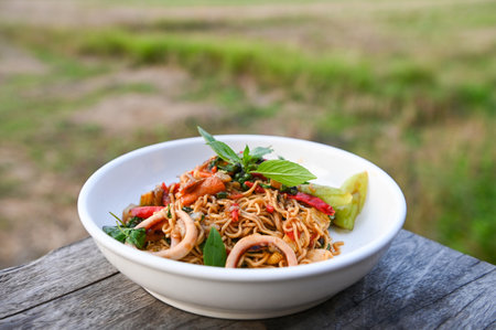 noodles plate with instant noodles stir fried with vegetables herb spicy tasty appetizing asian noodles mix seafood stir fried squid with basil and chilli pepperの写真素材