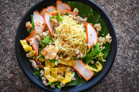 yellow noodles Thai food - dried noodles food on plate with condiment minced pork lemon lime peanuts dumpling red pork on plateの写真素材