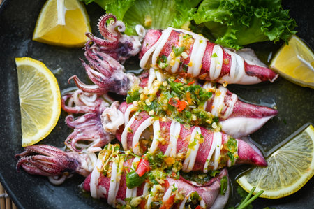 Thai food seafood plate with herb and spices, Steamed squid with lemon spicy chili and lemon sauce squid steamed with lime - top viewの写真素材