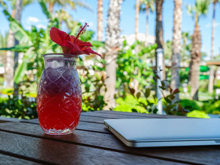 a red alcoholic cocktail and laptop on the tableの写真素材