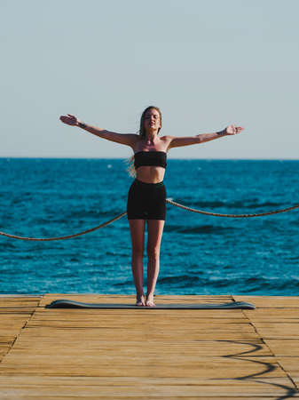 young woman doing yoga on the beach