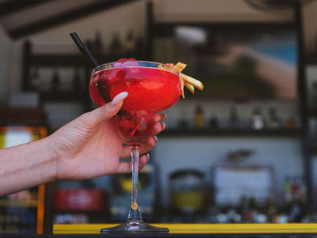 colorful cocktail in the hand of a girl at the bar