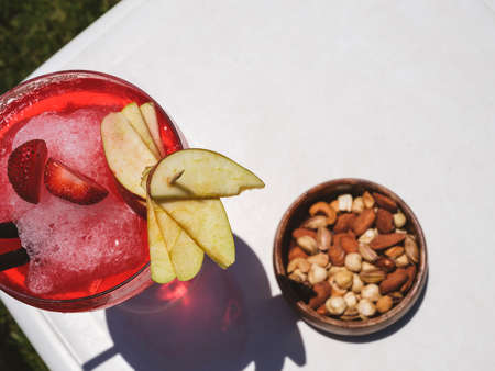 a red cocktail and nuts on the tableの写真素材