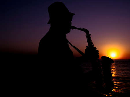 a musician playing the saxophone at sunsetの写真素材