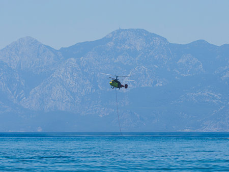 A firefighting helicopter carrying water to a forest fireの写真素材