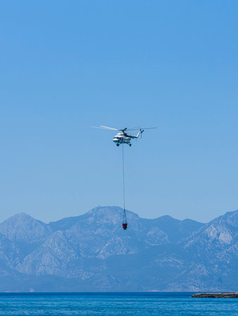 A firefighting helicopter carrying water to a forest fireの写真素材