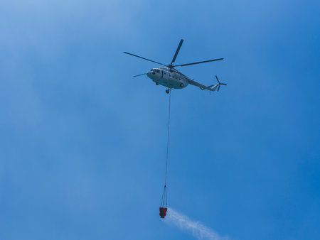 A firefighting helicopter carrying water to a forest fire