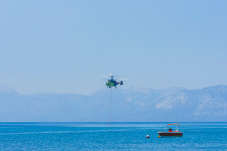 A firefighting helicopter carrying water to a forest fireの写真素材