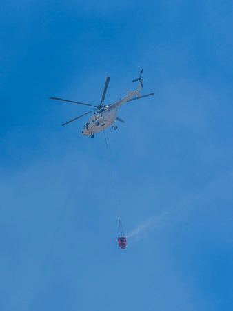 A firefighting helicopter carrying water to a forest fire