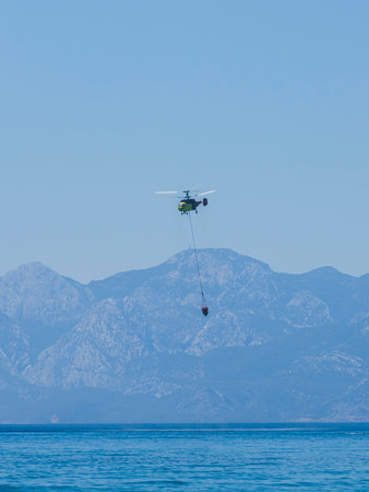 A firefighting helicopter carrying water to a forest fireの写真素材