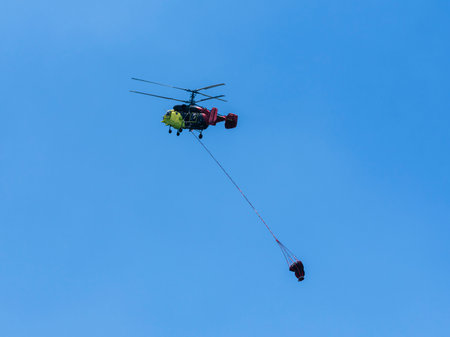 A firefighting helicopter carrying water to a forest fireの写真素材