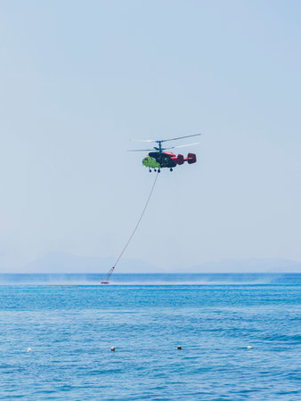 A firefighting helicopter carrying water to a forest fireの写真素材