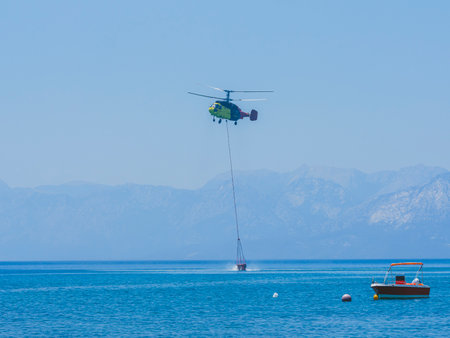 A firefighting helicopter carrying water to a forest fireの写真素材
