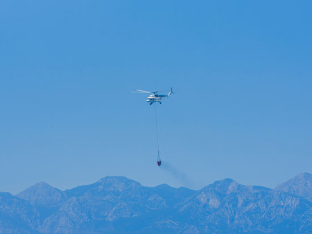 A firefighting helicopter carrying water to a forest fireの写真素材