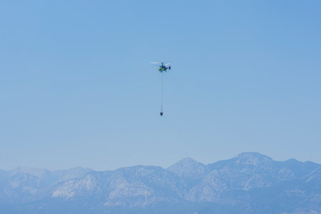 A firefighting helicopter carrying water to a forest fireの写真素材