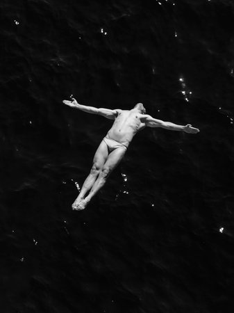 man jumping off rock into seaの写真素材