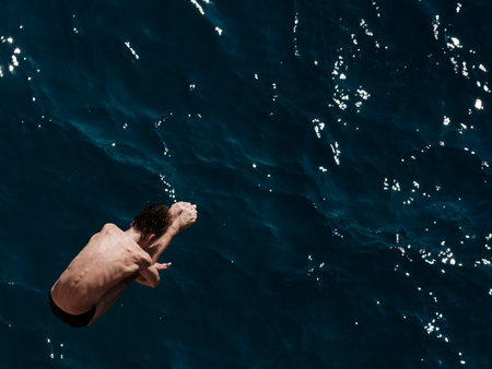 man jumping off rock into sea
