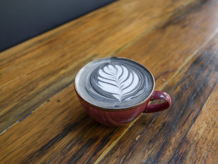 Fresh latte coffee in red mug on rustic tableの写真素材