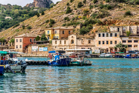 Balaklava(Balaclava), Sevastopol, Crimea, Russia - September 13, 2018: Black Sea. Harbor in the bay of Balaklava. Yachts and boats on the background of the embankment with old abandoned buildings.のeditorial素材