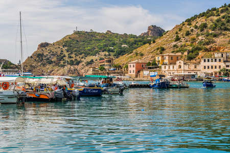 Balaklava(Balaclava), Sevastopol, Crimea, Russia - September 13, 2018: Black Sea. Harbor in the bay of Balaklava. Yachts and boats on the background of the embankment with old abandoned buildings.のeditorial素材