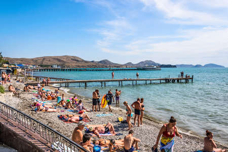 Koktebel, Feodosia, Republic of Crimea - September 9, 2018: Black sea. City beach, ship pier in the background of the steppe mountainsのeditorial素材