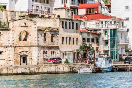Balaklava, Sevastopol, Republic of Crimea - September 13, 2018: Old and modern buildings on the embankment of the Black Sea bay. Boat, carsのeditorial素材
