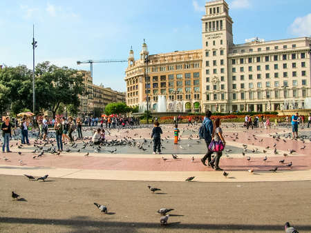 Barcelona, Spain - October 14, 2013: On Plaza Catalunya. Sunny autumn day. A lot of holidaymakers. People feed urban pigeonsのeditorial素材