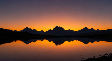 a breathtaking sunset over mountains reflected in the calm waters of a serene lake.の素材