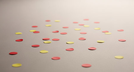 Scattered red and yellow confetti on a surface, perfect for party backgrounds.の素材