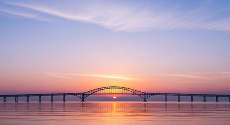 A scenic sunset over a bridge and water creates a tranquil and beautiful landscape.の素材