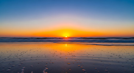golden hour on the beach with the sun setting over the ocean and reflecting on sandの素材