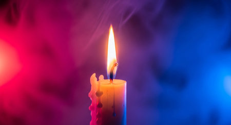 Burning candle in the dark with blue and pink smoke, close upの素材