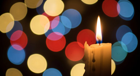 Burning candle on colorful bokeh background, close-upの素材