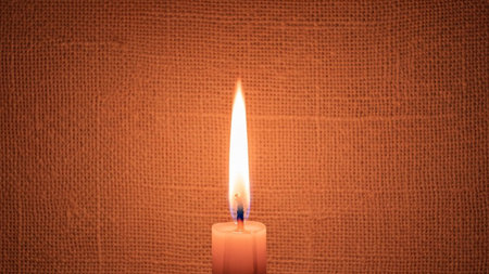 Burning candle on a background of brown burlap close-upの素材