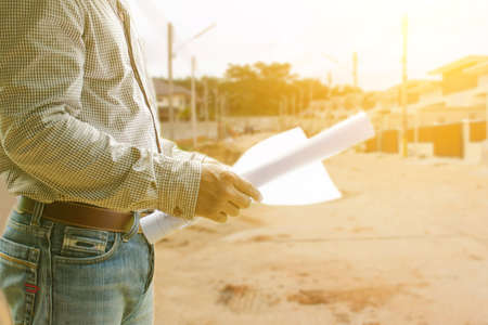 Man architect with  house plans in his hand on background of site construction.の写真素材
