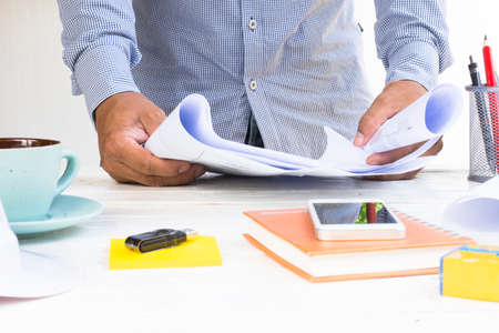 Man architect with  house plans in his hand and equipment on white table.Zoom in