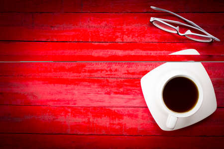 Background coffee cup and glasses on wooden red table background with black border.