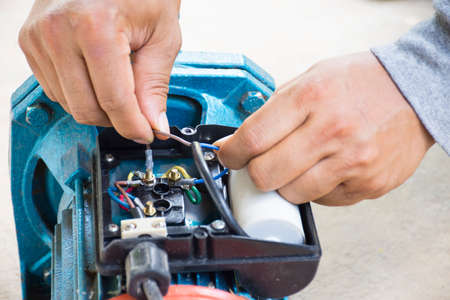 Electric motor  and man working equipment repair on cement floor background.Background motor or equipment.Close up.の写真素材