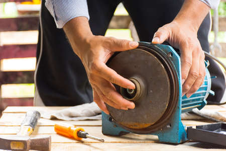 Electric motor  and man working equipment repair on wooden floor background.Background mechanic or equipment.Zoom inの写真素材