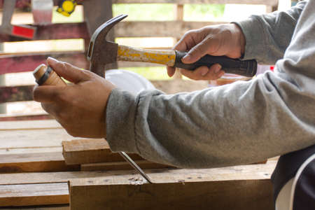 Carpenter using  chisel and hammer in his hand with plank.Close up and stillife.の写真素材