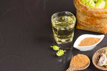 Noni fruit  and noni juice with noni powder on black table.Fruit for health and herb for health.の写真素材