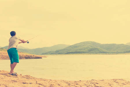 Young man fishing on the lake.Zoom in.の写真素材